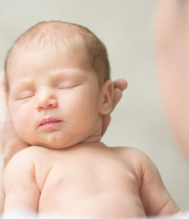 Portrait of a newborn hold in father palms Portrait of a newborn hold in father palms, eyes closed. Family, healthy birth concept photo. View over the shoulder